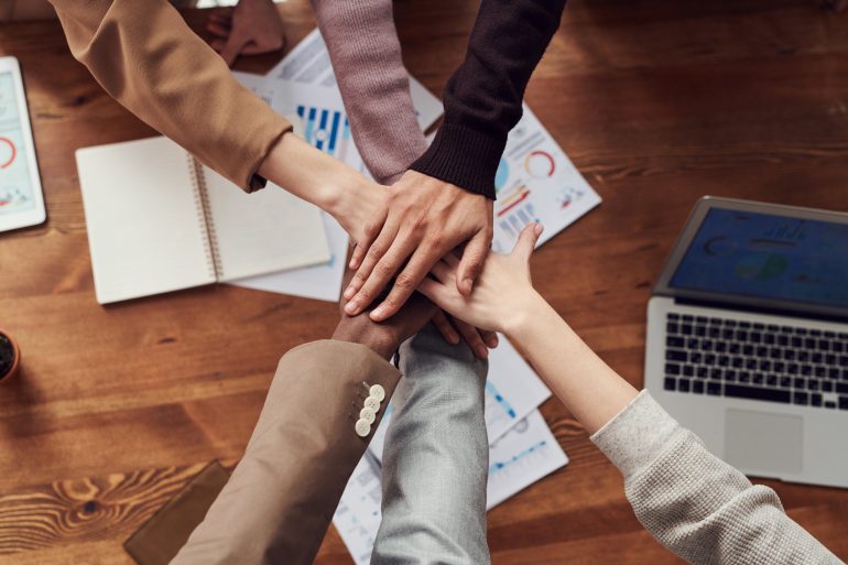 Verschillende mensen die hun handen op elkaar houden als teamverband