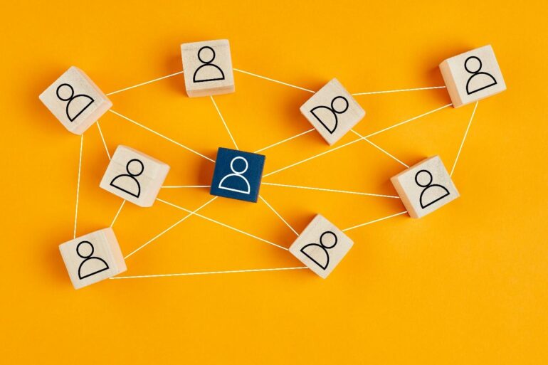 Houten blokjes met iconen van mensen erop die verbonden zijn door lijnen, als ware een spinnenweb. Bedoeld om een community te illustreren. 
